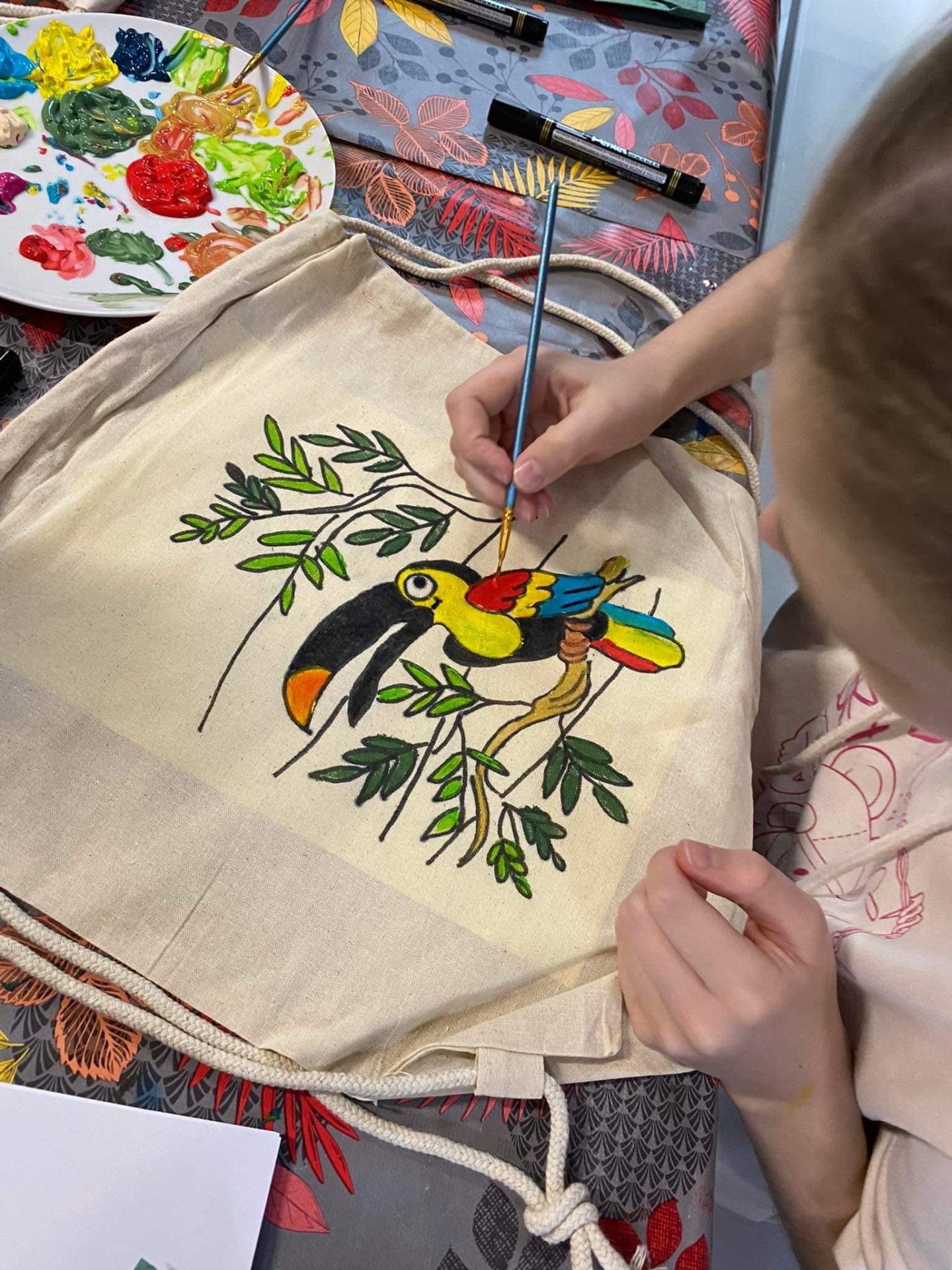 Dziewczynka malująca farbami na torbie tukana