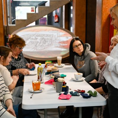Kobiety przy stole podczas warsztatów tworzenia kokard na szyję