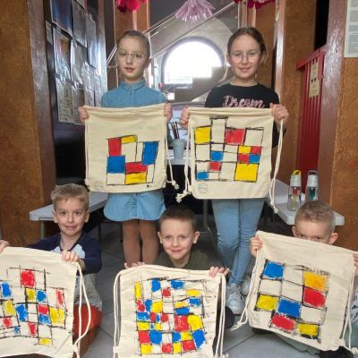 Dzieci z pomalowanymi torbami, inspirowanymi twórczością Pieta Mondriana