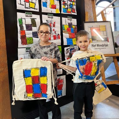 Dwoje dzieci z pomalowanymi torbami w czerwone, niebieskie i żółte kwadraty