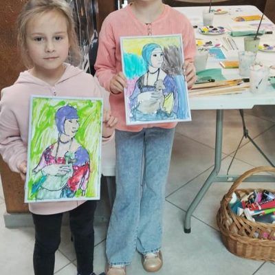 Zdjęcie dwóch dziewczynek trzymających namalowane przez siebie obrazki inspirowane obrazem 