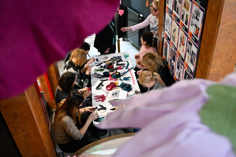 Widok z gory na kobiety przy stole podczas warsztatów tworzenia kokard-przypinek